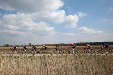 El grupo ciclista entre los que destacan el belga Wout Van Aert, cuarto por la izquierda, y el italiano Filippo Ganna, tercero por la derecha, atravesando un camino adoquinado.