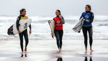 Tres surfistas salen del agua con sus licras de colores tras participar en una manga de la SuperLiga Siroko 2019, el circuito nacional de surf que visita Cantabria, Asturias, el Pa&iacute;s Vasco y Galicia.