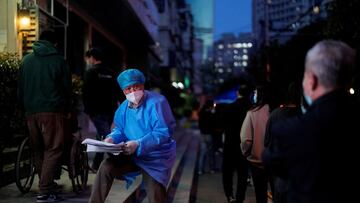 A worker in a protective suit directs residents lining up for nucleic acid test during a lockdown to curb the spread of the coronavirus disease (COVID-19) in Shanghai, China April 9, 2022. REUTERS/Aly Song