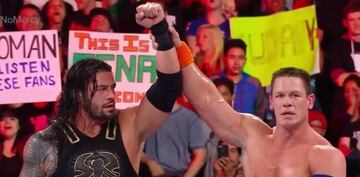John Cena alza el brazo de Roman Reings tras su combate en No Mercy.