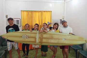 Giovanne Branzuela y sus vecinos sujetan la tabla de surf de Doug Falter encontrada en la isla de Sarangani (Filipinas) dos años después de su pérdida en Hawái.