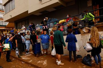 La gente hace cola para recibir alimentos y productos esenciales, tras las inundaciones provocadas por las fuertes lluvias, en Massanassa.