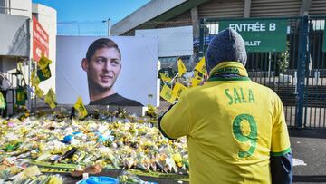 Supporters pay a tribute and look at yellow flowers displayed in front of the portrait of Argentinian forward Emiliano Sala at the Beaujoire stadium in Nantes, on February 10, 2019. - FC Nantes football club announced on February 8, 2019 that it will free