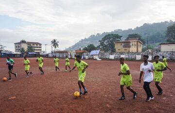 Los miembros del equipo de ftbol del Centro de Servicios Correccionales de mujeres calientan durante el entrenamiento en el campo de ftbol comunitario Parade en Freetown.