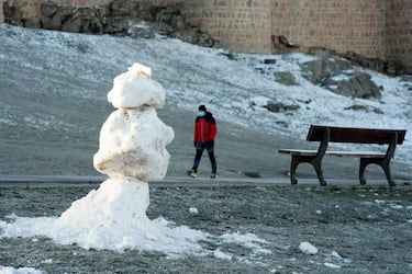 Un hombre pasea junto al lienzo norte de la muralla de Ávila donde la nieve ha dado paso al hielo por las bajas temperaturas registradas durante la madrugada. 