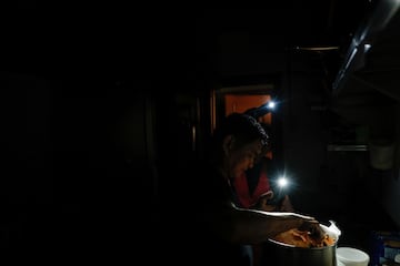 Un cocinero del restaurante de comida casera para llevar "La Cocinona" trabaja en una cocina oscura con la ayuda de las linternas de su telfono, durante un apagn en Madrid, Espa?a.