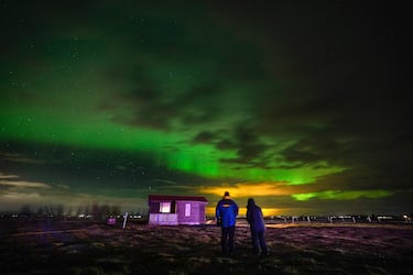 Personas observan la aurora boreal en una granja en Arabaer, cerca de Selfoss, Islandia.