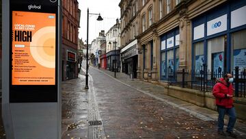 A man walks past an NHS sign displaying the Local Covid Alert Level as 'high' in Bradford, west Yorkshire on October 31, 2020, - British Prime Minister Boris Johnson is considering imposing a new lockdown across England within days following warnings his localised restrictions strategy has failed to curb soaring coronavirus rates, reports said Saturday. (Photo by Paul ELLIS / AFP)