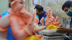 Artisans wearing a facemask paint clay idols of the Elephant Headed Hindu God Lord Ganesha at a workshop in Mumbai on June 26, 2020. (Photo by SUJIT JAISWAL / AFP)