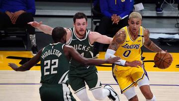 Mar 31, 2021; Los Angeles, California, USA; Los Angeles Lakers forward Kyle Kuzma (0) is defended by Milwaukee Bucks forward Khris Middleton (22) and guard Pat Connaughton (24) in the second half at Staples Center. Mandatory Credit: Kirby Lee-USA TODAY Sports