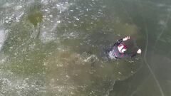 Piloto de moto nieve intentando salir del agua tras el hundimiento de su snowmobile en el lago helado. 