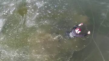 Piloto de moto nieve intentando salir del agua tras el hundimiento de su snowmobile en el lago helado. 