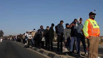 A member of the Johannesburg metro Police department (JMPD) keeps watch as stranded commuters wait for transportation at a bus terminal during a protest by taxi operators over the government's financial relief for the taxi industry, amid the coronavi