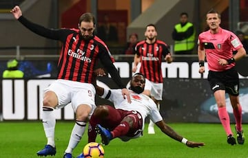 AC Milan's Argentine forward Gonzalo Higuain (L) vies with with Torino's Cameroonian defender Nicolas Nkoulou during the Italian Serie A football match between AC Milan and Torino at the San Siro stadium in Milan on December 9, 2018.