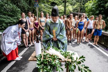 Descubre los mejores saltos desde la plataforma de 27 metros en Takachiho durante los primeros días de competición de la cuarta parada de la Serie Mundial Red Bull Cliff Diving 2023. En la foto, los clavadistas (al fondo) observan un ritual tradicional de purificación antes del comienzo.