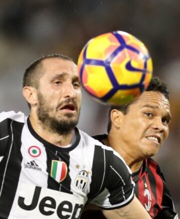 Juventus' Giorgio Chiellini (L) vies for the ball against AC Milan's Carlos Bacca during the Italian Super Cup final match between AC Milan and Juventus in Doha on December 23, 2016. / AFP PHOTO / KARIM JAAFAR