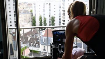 Aude looks at the track on her computer's screen as she practises on an exercise bike in her apartment, on April 20, 2020 in Paris on the 35th day of a strict lockdown aimed at curbing the spread of the COVID-19 pandemic,caused by the novel coronavirus. (Photo by FRANCK FIFE / AFP)