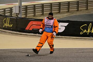 Un comisario de pista limpia el asfalto de escombros durante la carrera del GP de Bahréin.