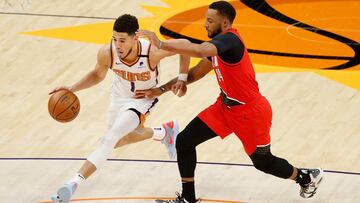 PHOENIX, ARIZONA - MAY 13: Devin Booker #1 of the Phoenix Suns drives the ball against Norman Powell #24 of the Portland Trail Blazers during the second half of the NBA game at Phoenix Suns Arena on May 13, 2021 in Phoenix, Arizona. The Suns defeated the 