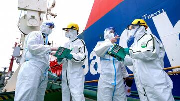 Police officers (L and 2nd R) wearing protective gear explain pandemic prevention information to fight against the spread of Covid-19 coronavirus to workers at Nanjing port in China's eastern Jiangsu province on August 4, 2021. (Photo by STR / AFP) / China OUT