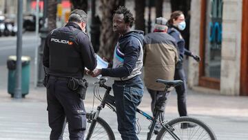 Un agente de Policía en un control en Valencia con un ciclista en el tercer día laborable del estado de alarma para comprobar que los ciudadanos siguen las indicaciones de permanecer en casa, en Valencia / Comunidad Valenciana / Españ