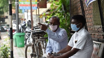 Men wearing protective facemasks as a preventive measure against the spread of the COVID-19 coronavirus, sit on a public bench in Ahmedabad on August 17, 2020. - India's official coronavirus death toll soared past 50,000 on August 17 as the pandemic
