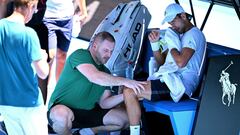 El tenista serbio Novak Djokovic recibe tratamientos en su rodilla izquierda durante su entrenamiento con Daniil Medvedev en el Open de Australia.