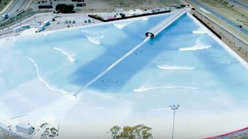 Vista a&eacute;rea de la piscina de olas artificiales con tecnolog&iacute;a Wavegarden Cove llamada URBNSurf Melbourne, situada en Australia, con varias olas rompiendo a la vez y algunos surfistas remando para llegar al pico. 