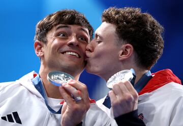 Comentario atribuido a Matthias Hangst, Director de Fotografía de Deportes en Getty Images:

Tom Daley ha completado ahora su set olímpico. Tras ganar la medalla de oro en los Juegos de Tokio, celebró su medalla de plata con su compañero de saltos, Noah Williams. Tom tuvo su primera experiencia en unos Juegos Olímpicos en Londres 2012 y volvió a la competición antes de París después de una pausa de dos años por una razón emotiva: Su hijo Robbie quería ver a su padre competir en unos Juegos Olímpicos. Fue un momento especial para el atleta británico capturado por el fotógrafo de Getty Images Clive Rose, que terminó en una celebración espontánea: un beso después de la ceremonia de premiación. Tom y su compañero de saltos Noah presentaron sus medallas de plata a su manera. El momento refleja todas las emociones y sentimientos liberados por estos atletas de alto rendimiento.