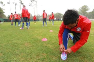 La selección chilena Sub 20 ya se prepara en Uruguay para el debut con Brasil este jueves a las 19:00. Diego Rojas se abrocha los zapatos en primer plano.