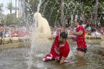 El defensa del Sevilla Coke se baña junto a otro compañero en la plaza de la Puerta de Jerez, durante el paseo triunfal que ha realizado el equipo esta tarde para festejar y ofrecer a la ciudad su quinta Liga Europa conseguida el pasado miércoles en Basilea (Suiza)