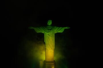 La estatua del Cristo Redentor en la montaña del Corcovado en Rio iluminado con los colores de la bandera de Brasil.