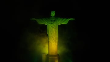 La estatua del Cristo Redentor en la montaña del Corcovado en Rio iluminado con los colores de la bandera de Brasil.