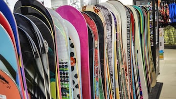 Varios tipos de tablas de snowboard de distintos colores puestas en vertical en una tienda de material de esqu&iacute; y snowboard.