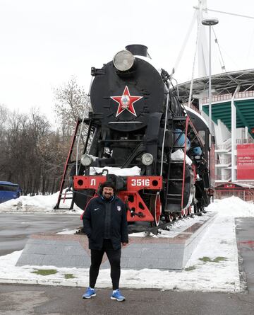 El Mono Burgos posa delante de una locomotora en los exteriores del estadio del Lokomotiv.