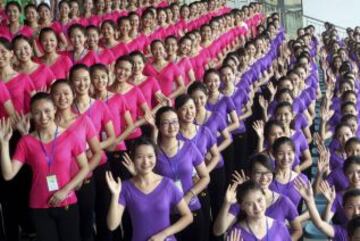 Las Voluntarias para los Juegos de la Juventud 2014, que se celebrarán en la ciudad china de Nanjing, saludan y sonríen durante un entrenamiento.