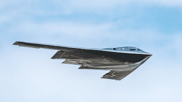 Rapid City, SD – May 14, 2022: A stealth B-2 bomber is in flight against a cloudy sky backdrop, showcasing its distinctive triangular shape and dark color as it passes over the Ellsworth Air Force Base. The aircraft is designed for low visibility on radar, performing what could be a routine exercise or a demonstration.