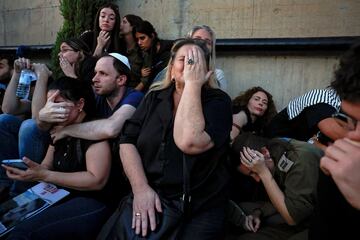 Amigos y familiares se refugian mientras suenan las sirenas de los cohetes durante el funeral de Sagiv Ben Zvi.