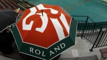 Algunos espectadores de resguardan de la lluvia con paraguas en Roland Garros (París)