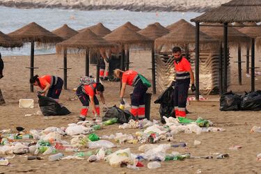 Miembros del servicio de limpieza municipal de Málaga recogen restos de basura en la playa de La Malagueta.