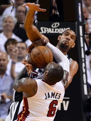 El jugador de los Spurs Tim Duncan (atrás) bloquea una jugada del jugador de los Heat de Miami LeBron James (en primer plano, de espaldas) durante el sexto partido de las finales que enfrentó a ambos equipos en el American Airlines Arena de Miami en Florida (Estados Unidos)