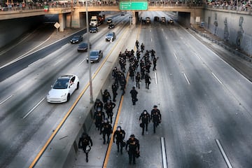 Agentes de policía hacen guardia en una carretera durante una protesta contra las redadas federales de inmigración, como se ve a través de una valla, en el centro de Los Ángeles.