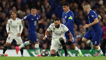 Mateo Kovacic observa la presión de Thiago Silva a Karim Benzema que trata de controlar el balón con una rodilla en el césped.