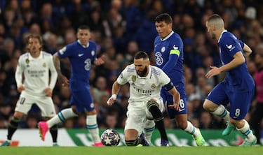 Mateo Kovacic observa la presión de Thiago Silva a Karim Benzema que trata de controlar el balón con una rodilla en el césped.