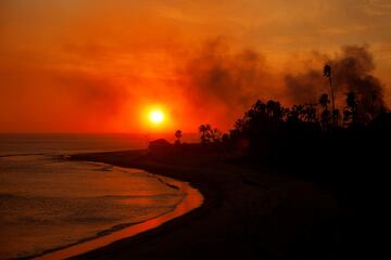 El sol se oculta tras una atmósfera anaranjada causada por los fuegos en Malibú, mientras el humo no deja de aparecer.