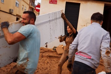 Voluntarios y vecinos ayudan a limpiar lugares afectados por las fuertes lluvias que provocaron inundaciones, en Paiporta.