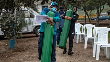 (FILES) In this file photo taken on July 29, 2020 relatives of COVID-19 patients move oxygen cylinders as they queue to recharge them in Villa Maria del Triunfo, in the southern outskirts of Lima. - Almost six months after it was first detected in Latin America, the coronavirus death toll has reached 250,000 and exacerbated the problems of poverty and inequality, threatening to undo a decade of slow social progress. (Photo by Ernesto BENAVIDES / AFP)