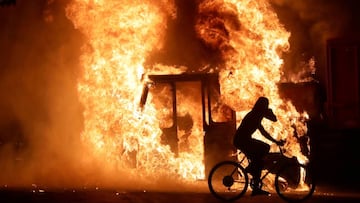 Un hombre en bicicleta pasa junto a un cami&oacute;n en llamas frente al Palacio de Justicia del Condado de Kenosha en Kenosha, Wisconsin, Estados Unidos, 23 de agosto de 2020.