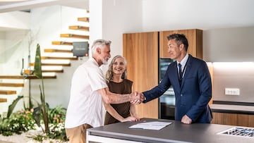 Senior couple signing house leasing agreement and shaking hands with asian real estate agent