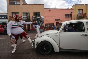 Los luchadores mexicanos Señor Jerry y Gran Felipe Jr. detienen un coche en plena calle para entregar mascarillas a sus pasajeros en Xochimilco, México. Se trata de una original campaña del gobierno local para concienciar a la población, por medio de la lucha libre, del uso de mascarillas como medida de prevención contra la COVID-19. 